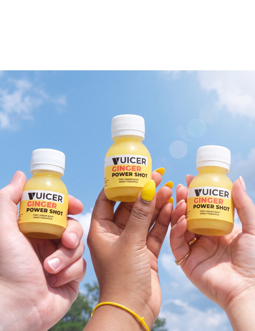 three people holding a vuicer ginger shot outside