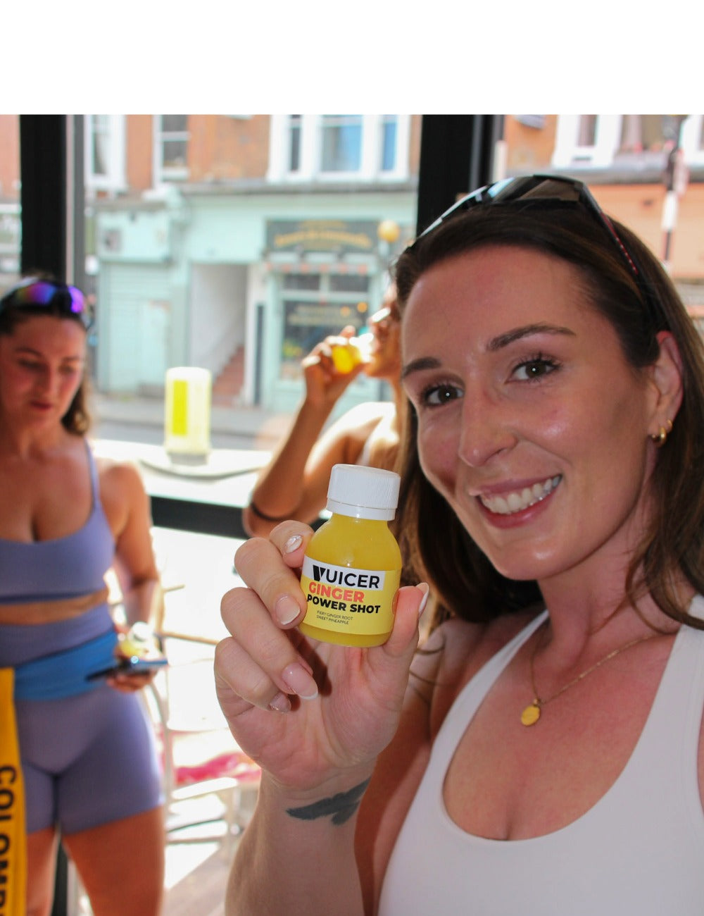 woman smiling holding a vuicer ginger shot